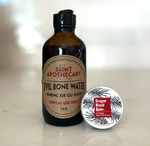 Bottle of Saint Apothecary Evil Bone Water and a container of Dragon Blood Balm on a light background